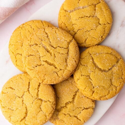 Small batch of chewy sugar cookies piled on a white marble platter.
