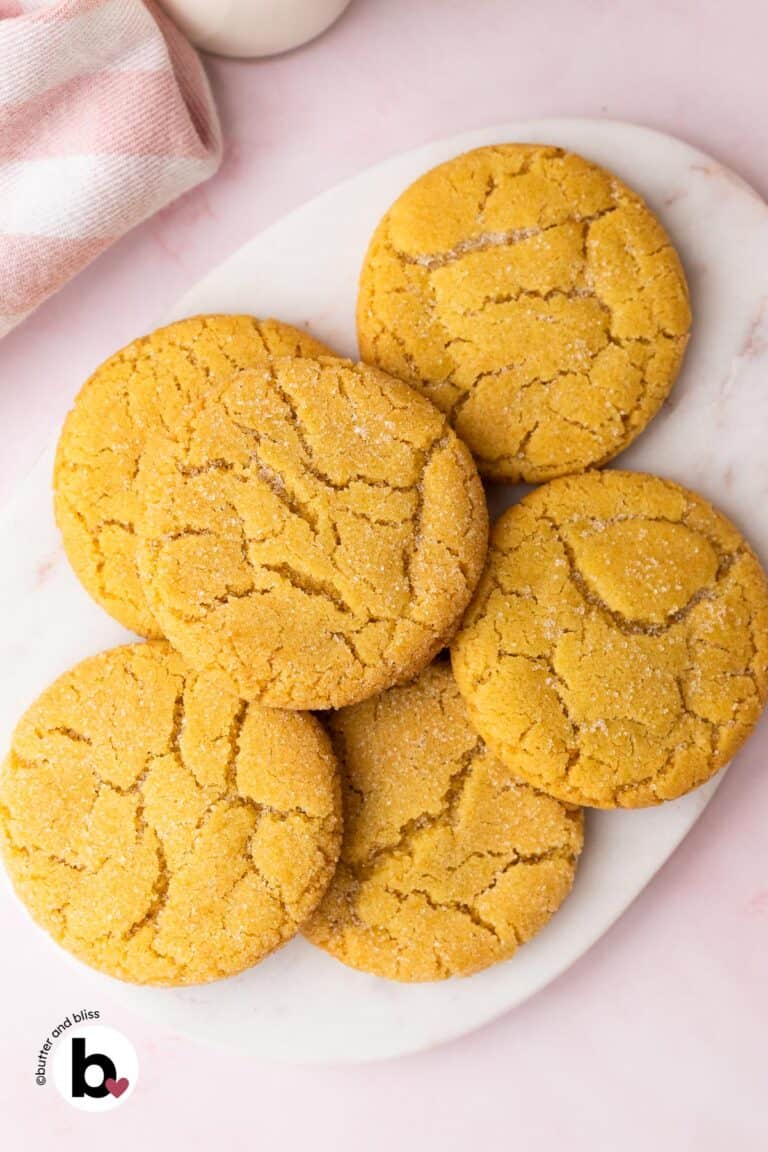 Small batch of chewy sugar cookies piled on a white marble platter.