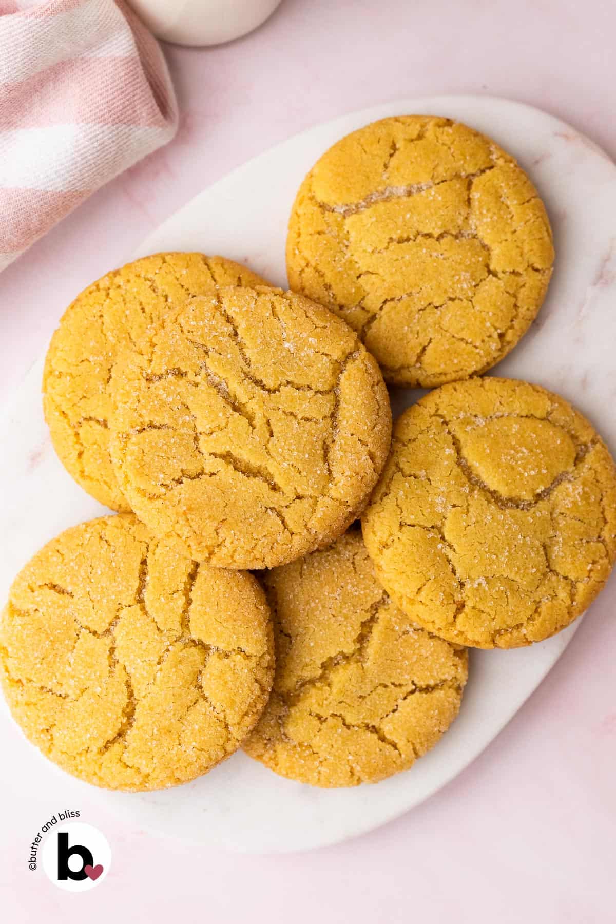 Small batch of chewy sugar cookies piled on a white marble platter.