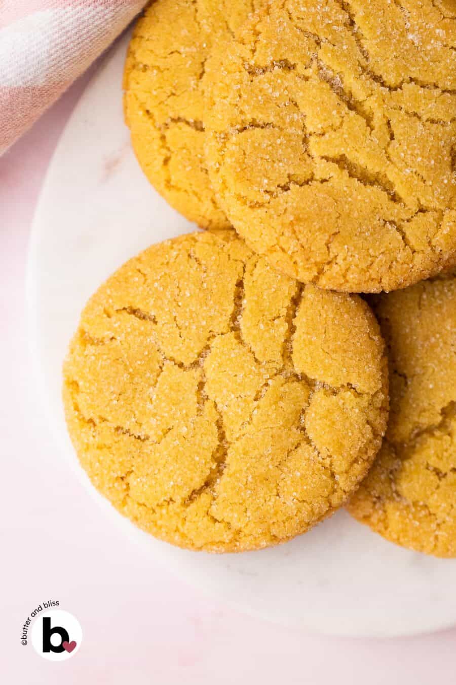 Chewy sugar cookies piled on a white plate.