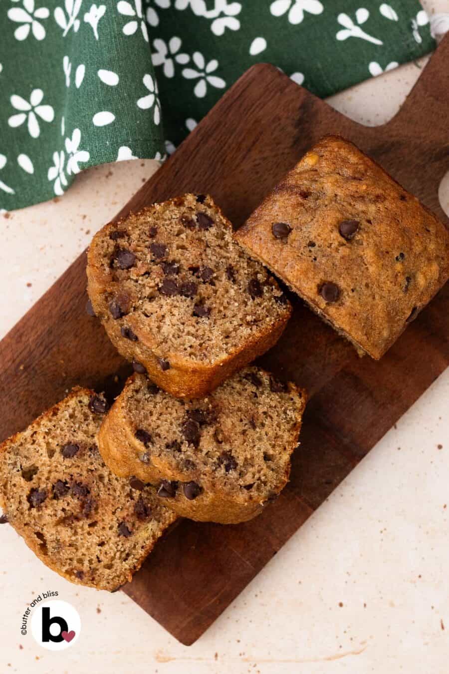 Mini chocolate chip banana bread loaf cut into slices on a wood board.