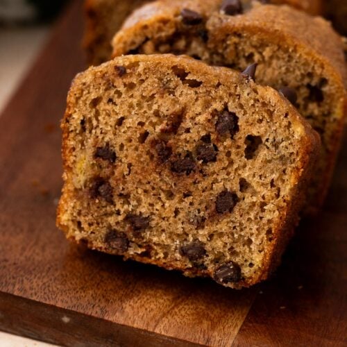 Slice of banana bread on a cutting board revealing chocolate chips throughout.