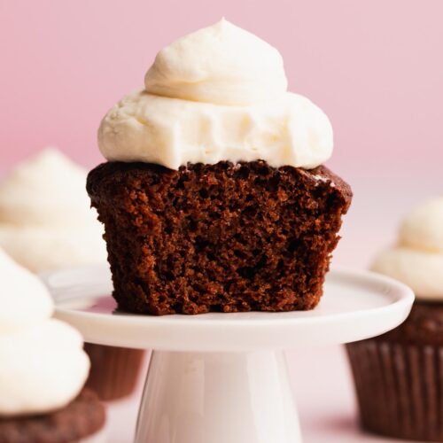 Single chocolate eggless cupcake cut in half revealing moist crumb on a mini cupcake stand.
