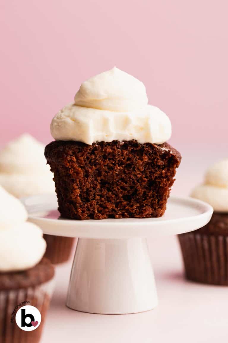 Single chocolate eggless cupcake cut in half revealing moist crumb on a mini cupcake stand.