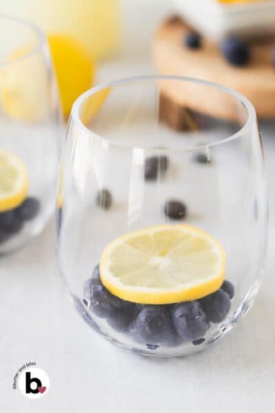 Lemon slice on top of blueberries in a glass.