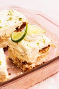 Slice of creamy lime icebox cake with layers of cookies and topped with lime wedge.