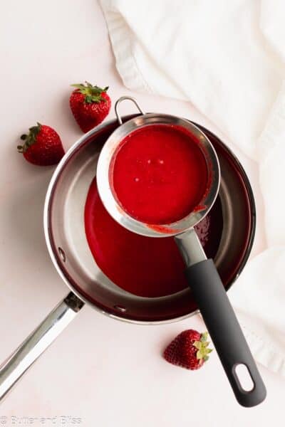 Strawberry puree strained through a strainer set over a saucepan.
