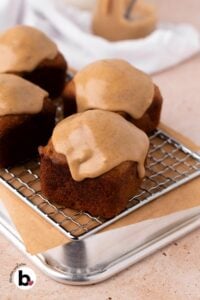 Individual apple banana bread loaves with icing on a wire rack.