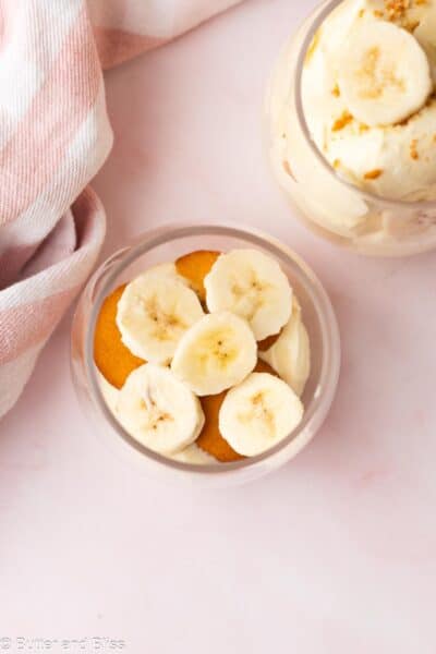 Banana pudding being assembled in parfait glasses.