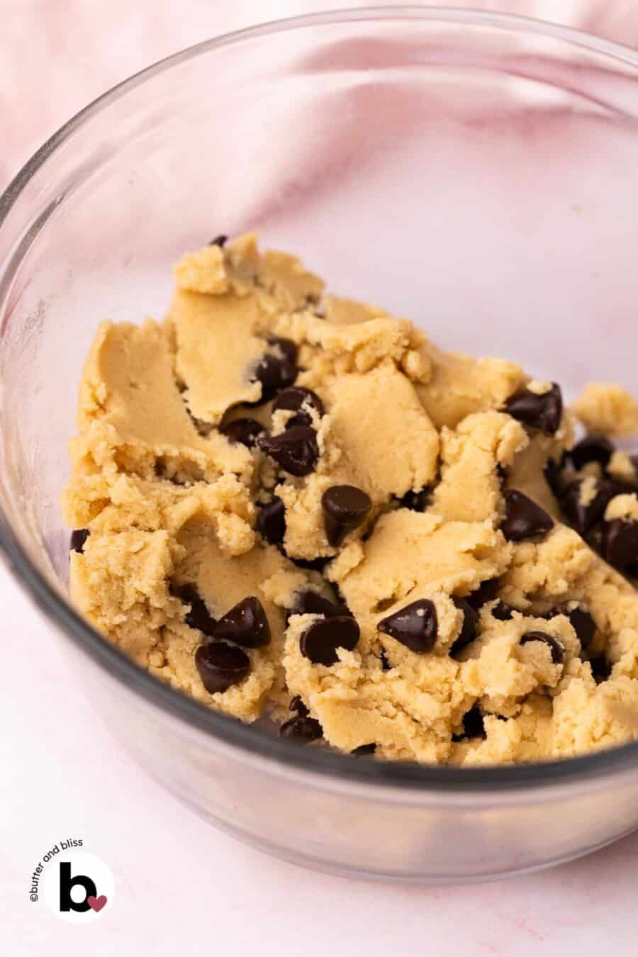 A mixing bowl with edible chocolate chip cookie dough and a pink napkin by Butter and Bliss.
