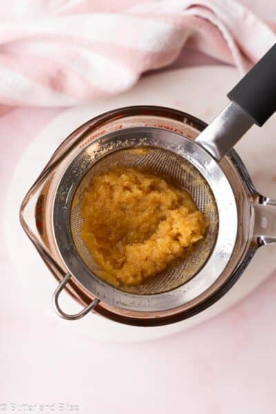Grated ginger being strained over a bowl.