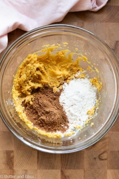 Creamed butter and sugar in a mixing bowl with flour and cocoa powder sprinkled on top.