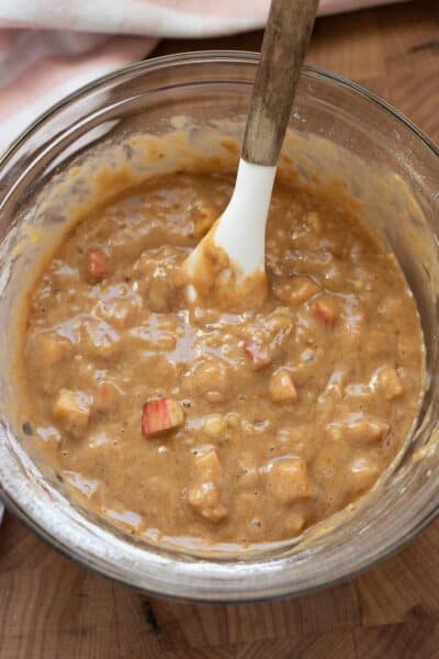Apple banana bread batter with chunks of apple in a mixing bowl.