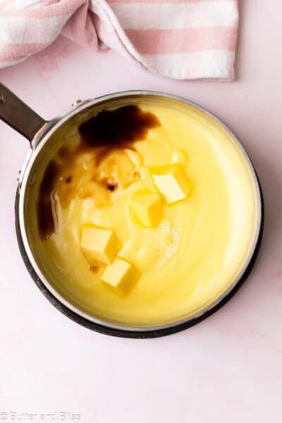 Vanilla pudding in a saucepan with butter and vanilla ready to be mixed.