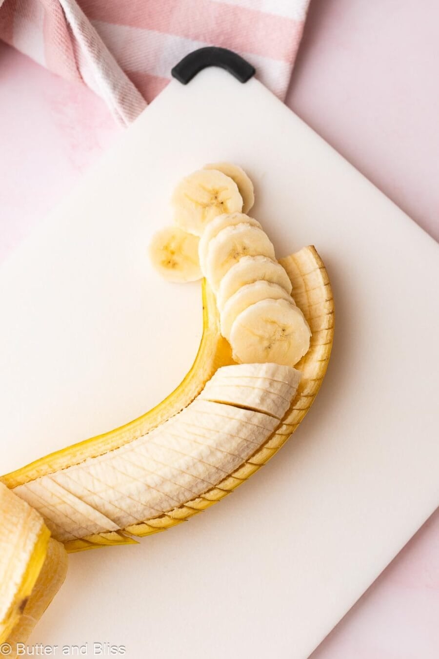 Fresh banana cut into slices on a cutting board.