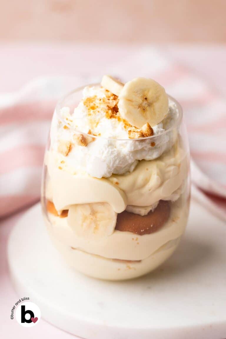 A single parfait glass of banana pudding topped with whipped cream and fresh banana slices.