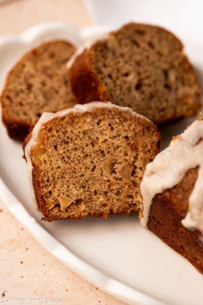 Slices of apple banana bread with caramel icing drizzle on a white plate.
