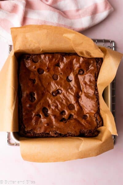 Crinkly top brownies freshly baked in a small square cake pan on a cooling rack.
