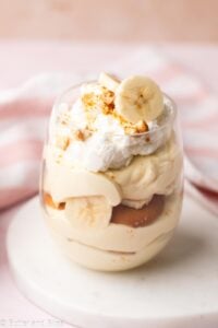 A single cup of banana pudding with layers of bananas, wafers, and creamy pudding.
