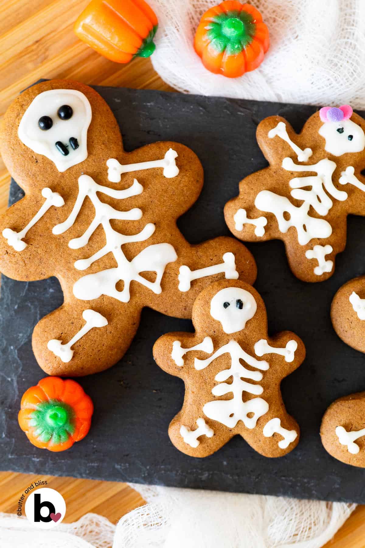 Gingerbread cookies decorated like cute skeletons for Halloween on a black plate.