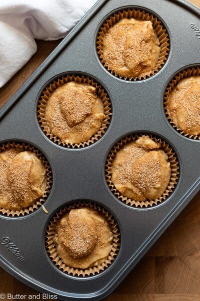 Banana nut muffin batter portioned into a muffin pan and topped with cinnamon sugar.