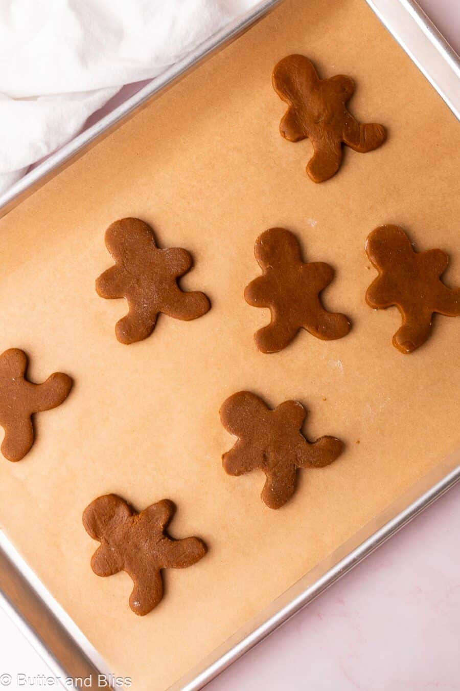 Gingerbread man cookies on a parchment lined baking sheet, redy to be baked.
