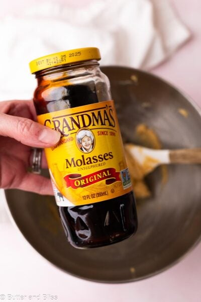 Hand holding a jar of molasses for gingerbread cookie dough.