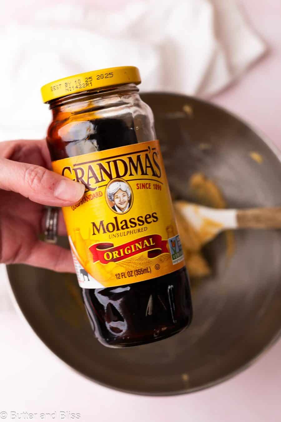 Hand holding a jar of molasses for gingerbread cookie dough.