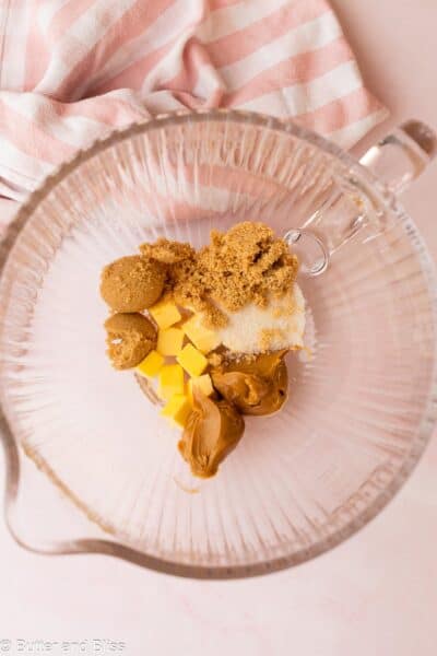 Butter, peanut butter, and sugars in a clean mixing bowl next to a pink napkin.