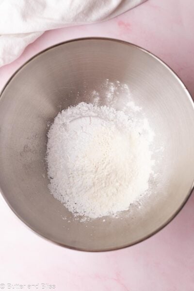 Powdered sugar and meringue powder in a silver mixing bowl.