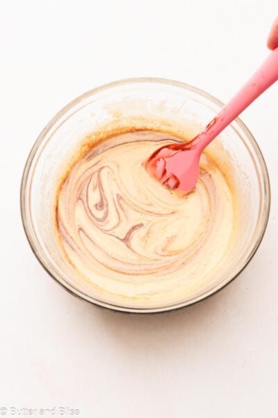 Melted chocolate being mixed in frothy egg white mixture in a small bowl.