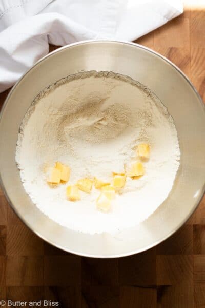 Butter cubes added to a mixing bowl of dry ingredients for the reverse creaming method.