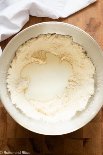 Liquid ingredients added to a mixing bowl of dry ingredients for a small cake.