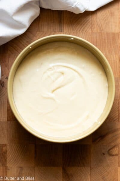 Smooth cake batter in a small round cake pan next to a white napking.