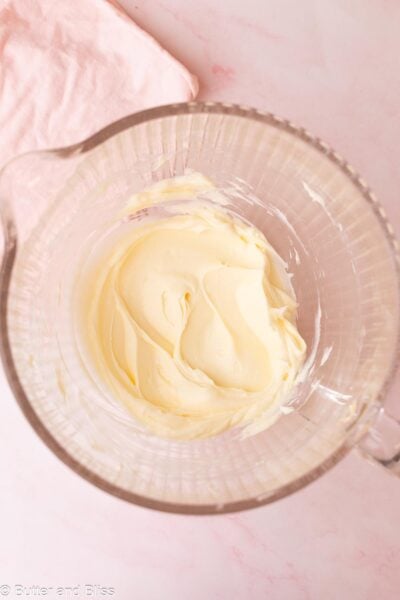 Smooth cream cheese and sugar mixture in a glass mixing bowl.
