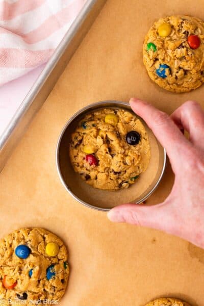 Hand shaping a perfectly round cookie by swirling it around inside a large round cutter.