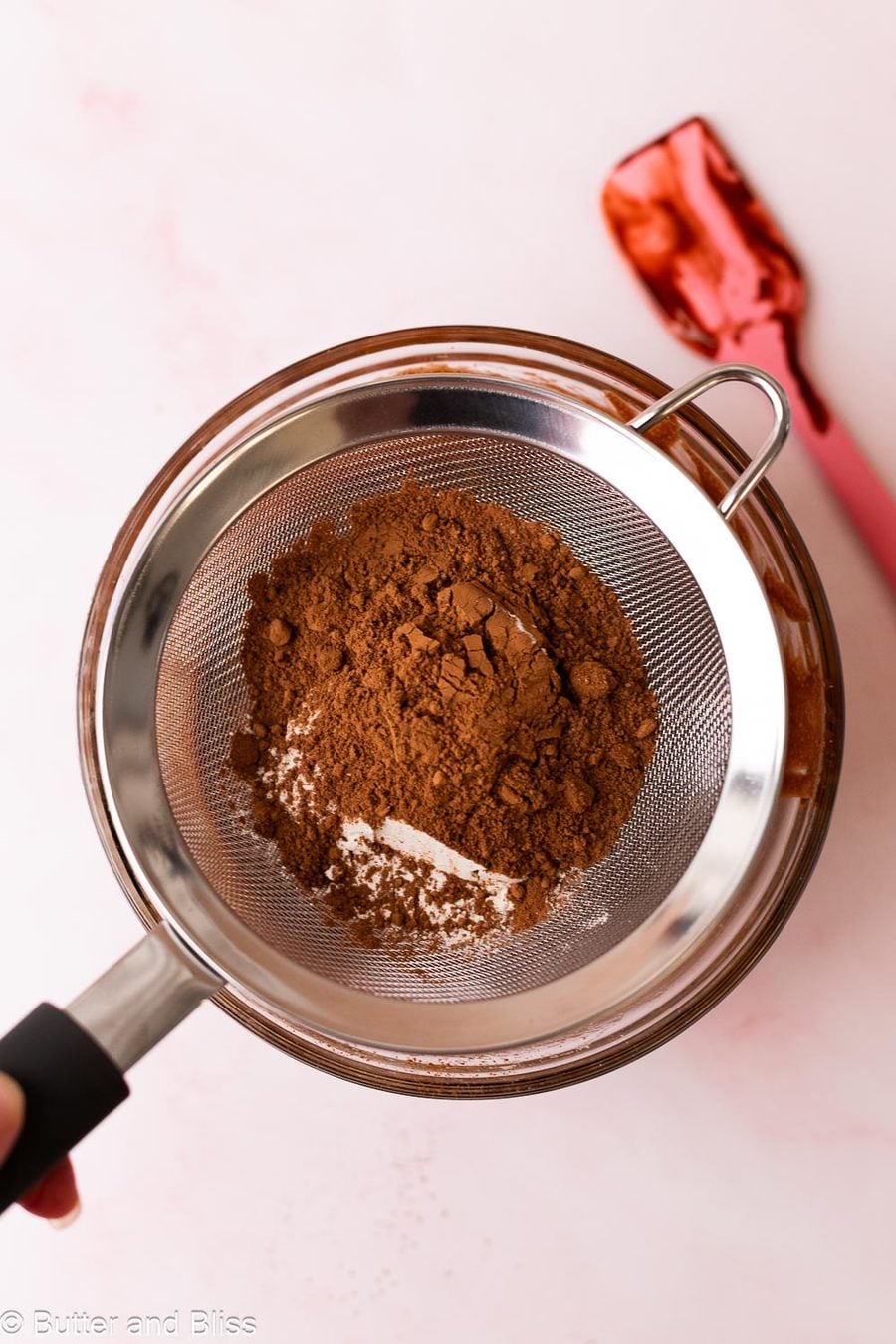Dry ingredients for brownies being sifted into a mixing bowl.