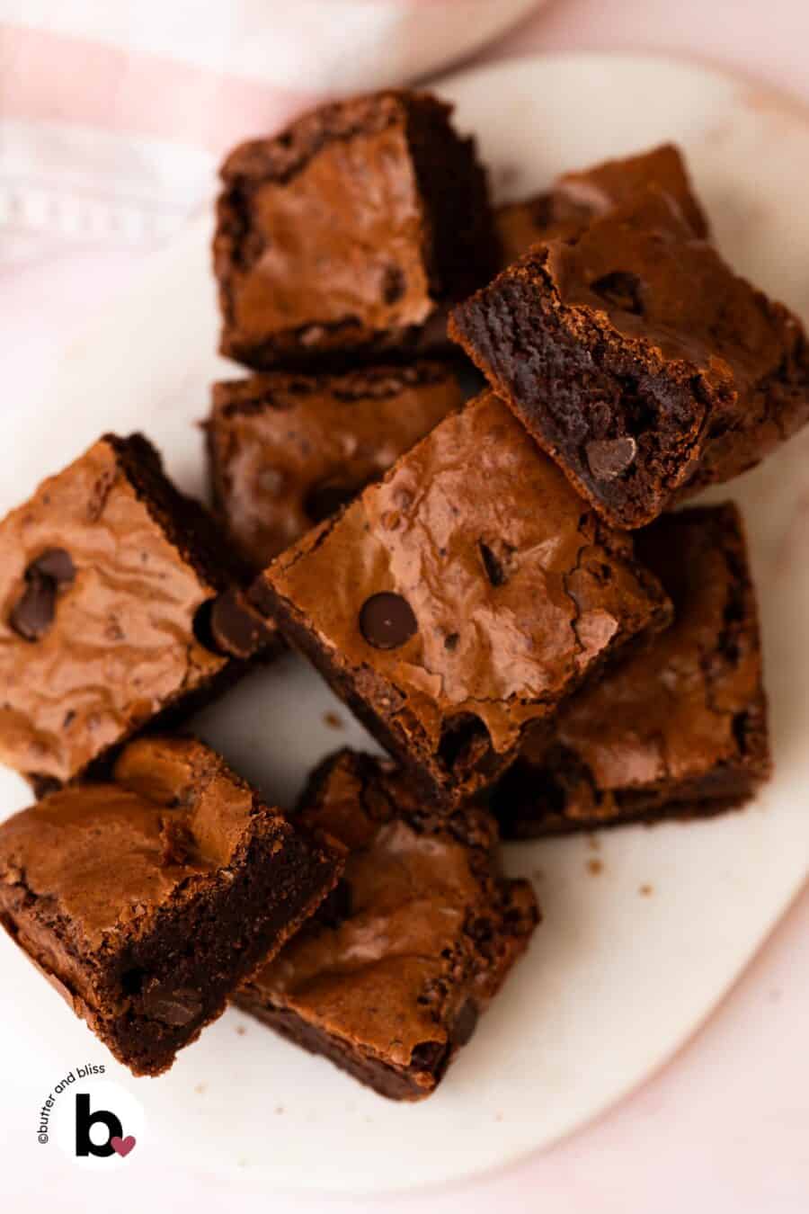 Small batch brownies topped with chocolate chips cut into squares and piled on a white plate.