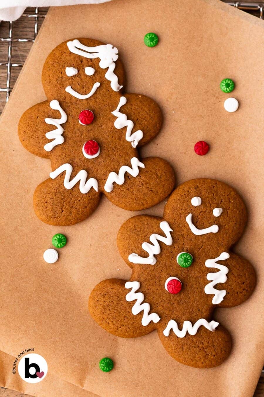 Two decorated gingerbread man cookies on a piece of parchment paper with holiday sprinkles.