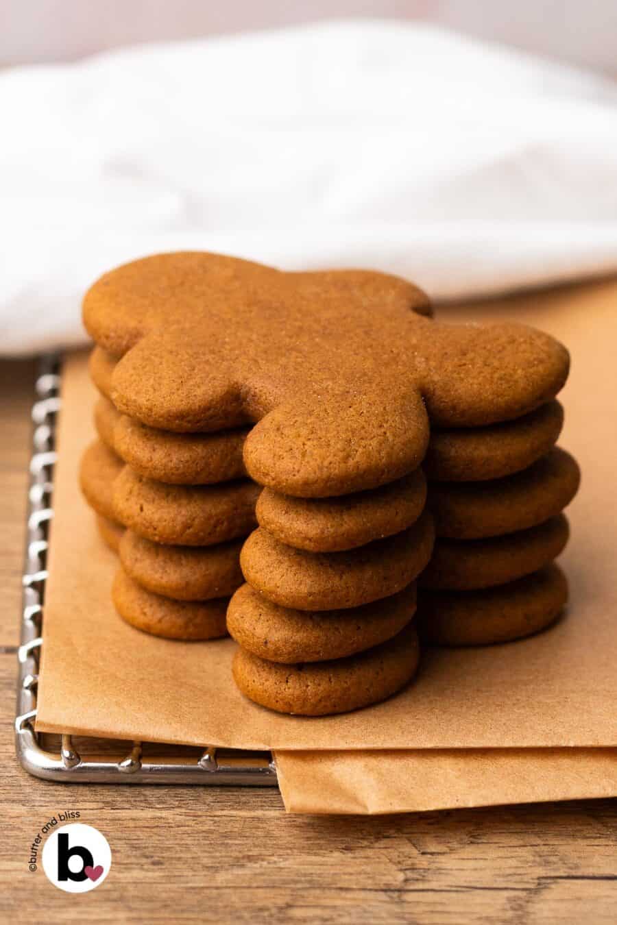 A small stack of gingerbread man cookies on a parchment lined wire rack.
