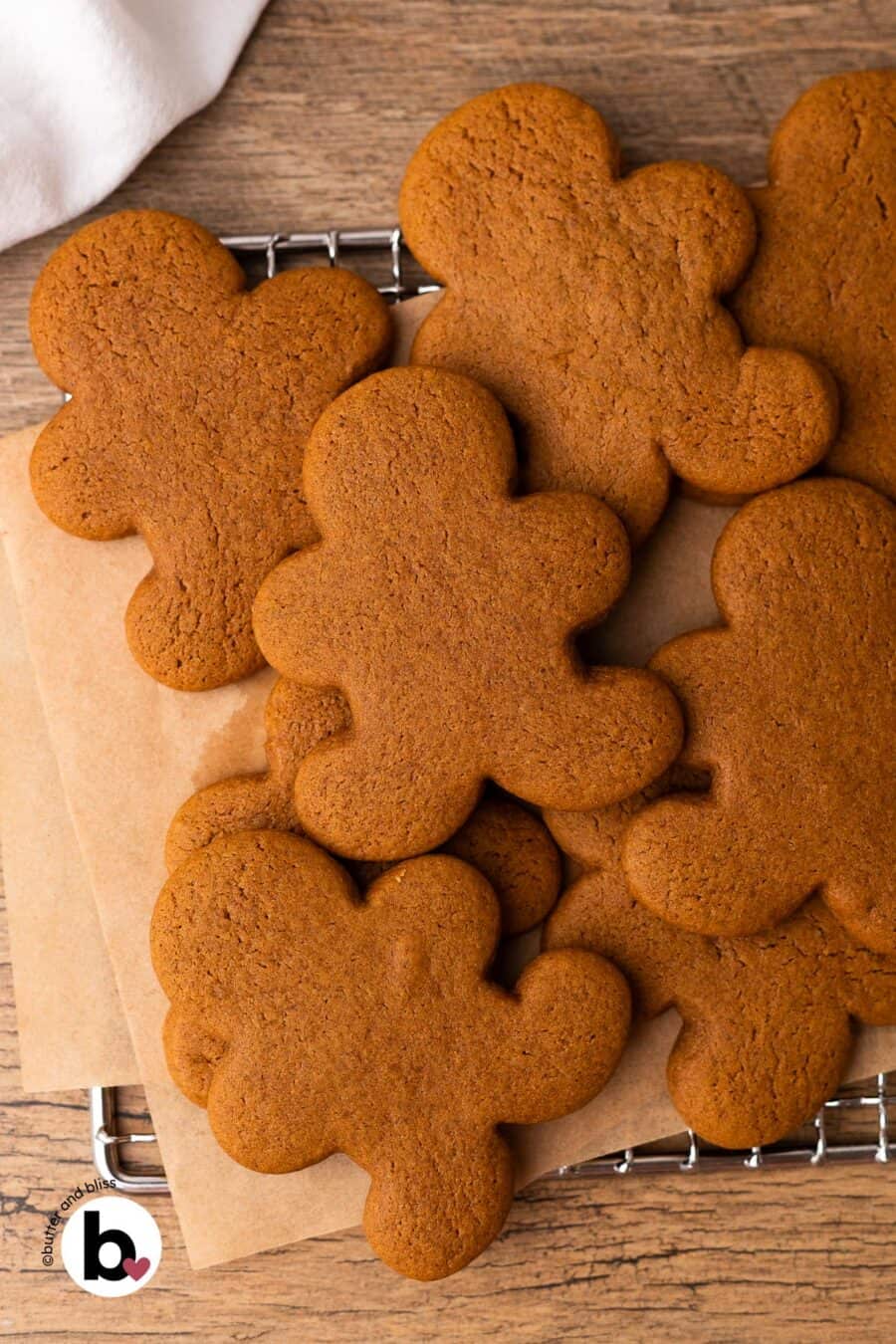 Freshly baked and undecorated gingerbread man cookies in a pile on a wire rack.