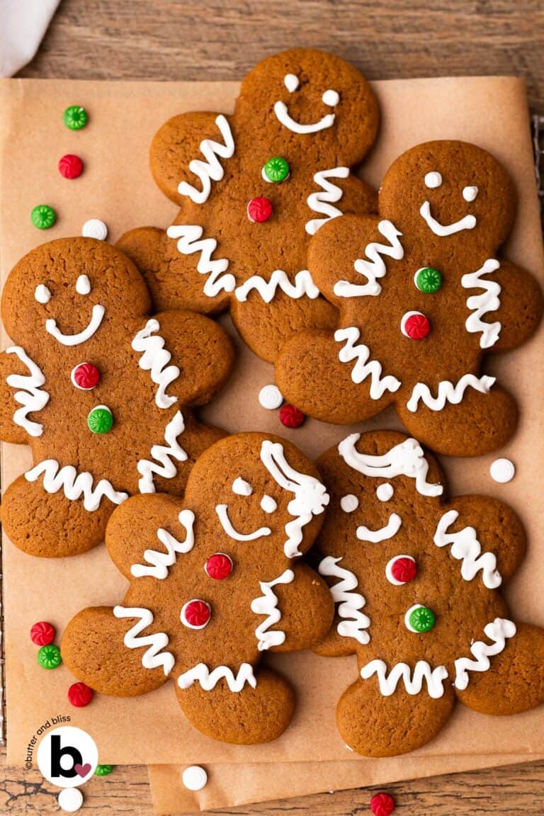 Gingerbread man cookies decorated with royal icing for Christmas on a piece of parchment paper.
