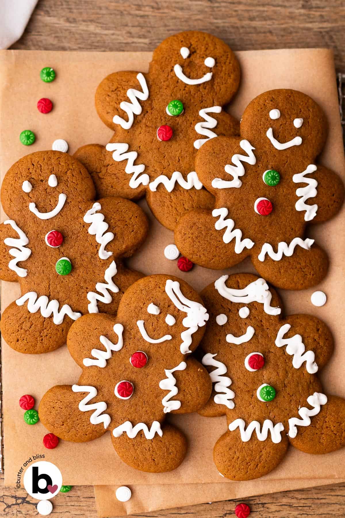 Gingerbread man cookies decorated with royal icing for Christmas on a piece of parchment paper.