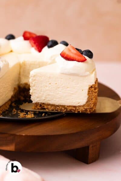 No-bake cheesecake slice with whipped cream and fruit topping on a cake server.