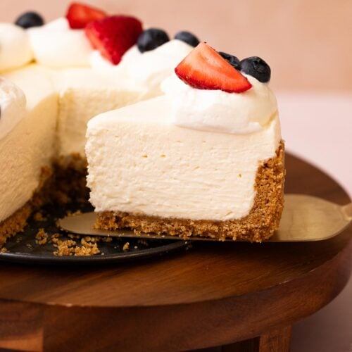 No-bake cheesecake slice with whipped cream and fruit topping on a cake server.