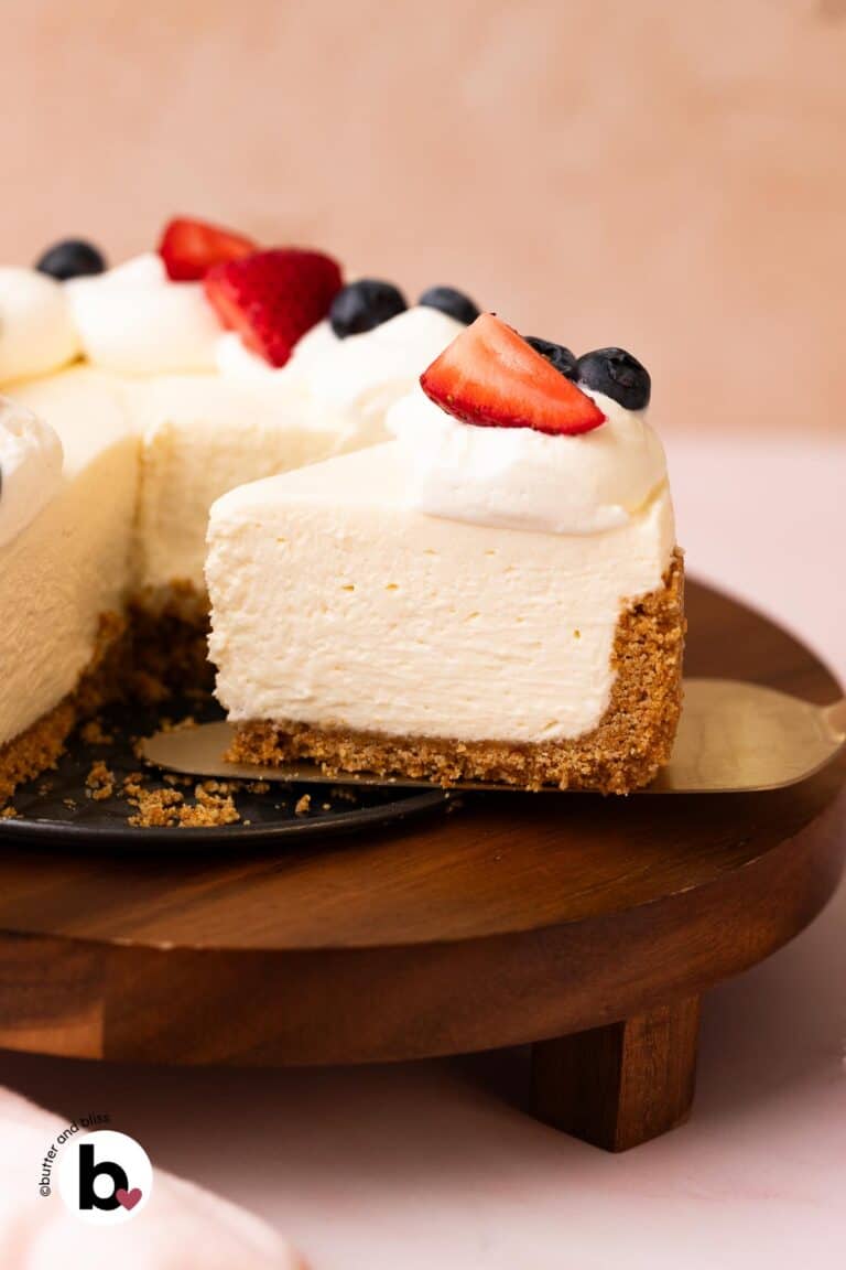 No-bake cheesecake slice with whipped cream and fruit topping on a cake server.
