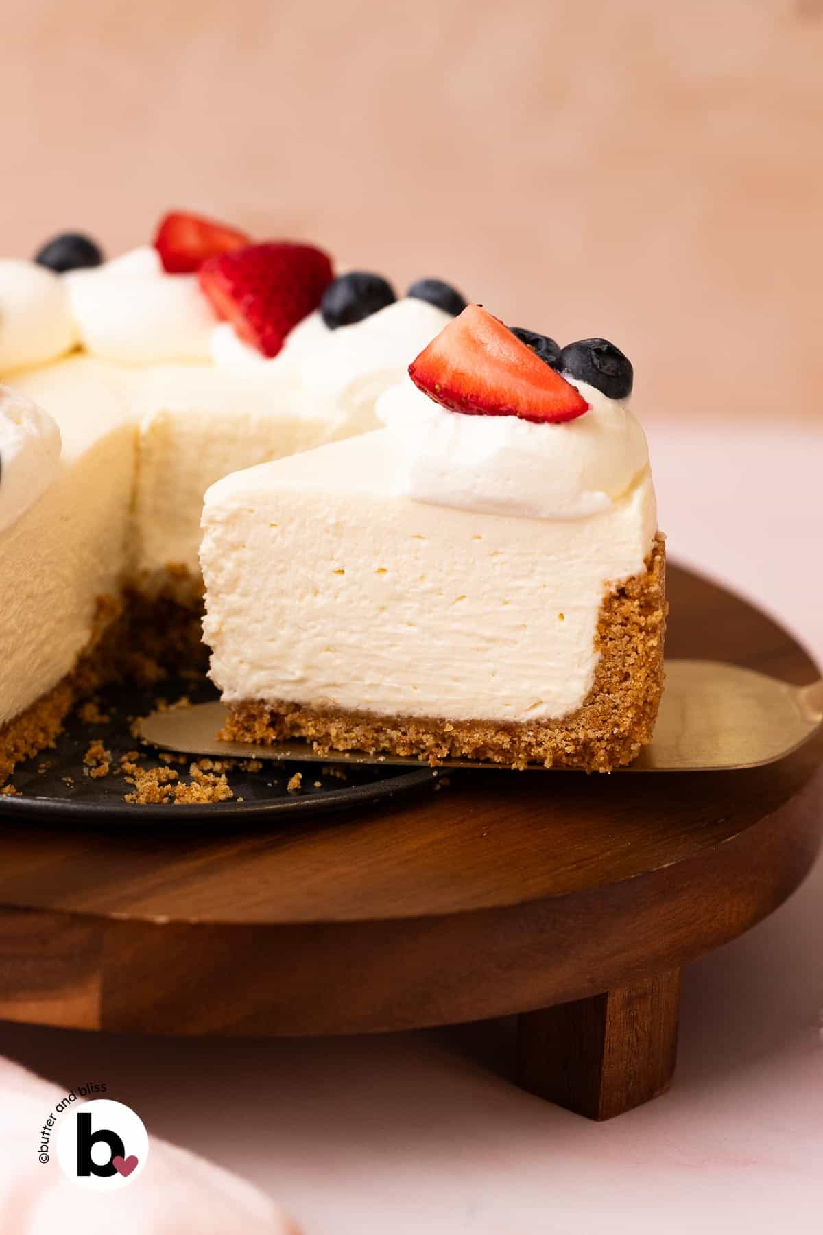 No-bake cheesecake slice with whipped cream and fruit topping on a cake server.
