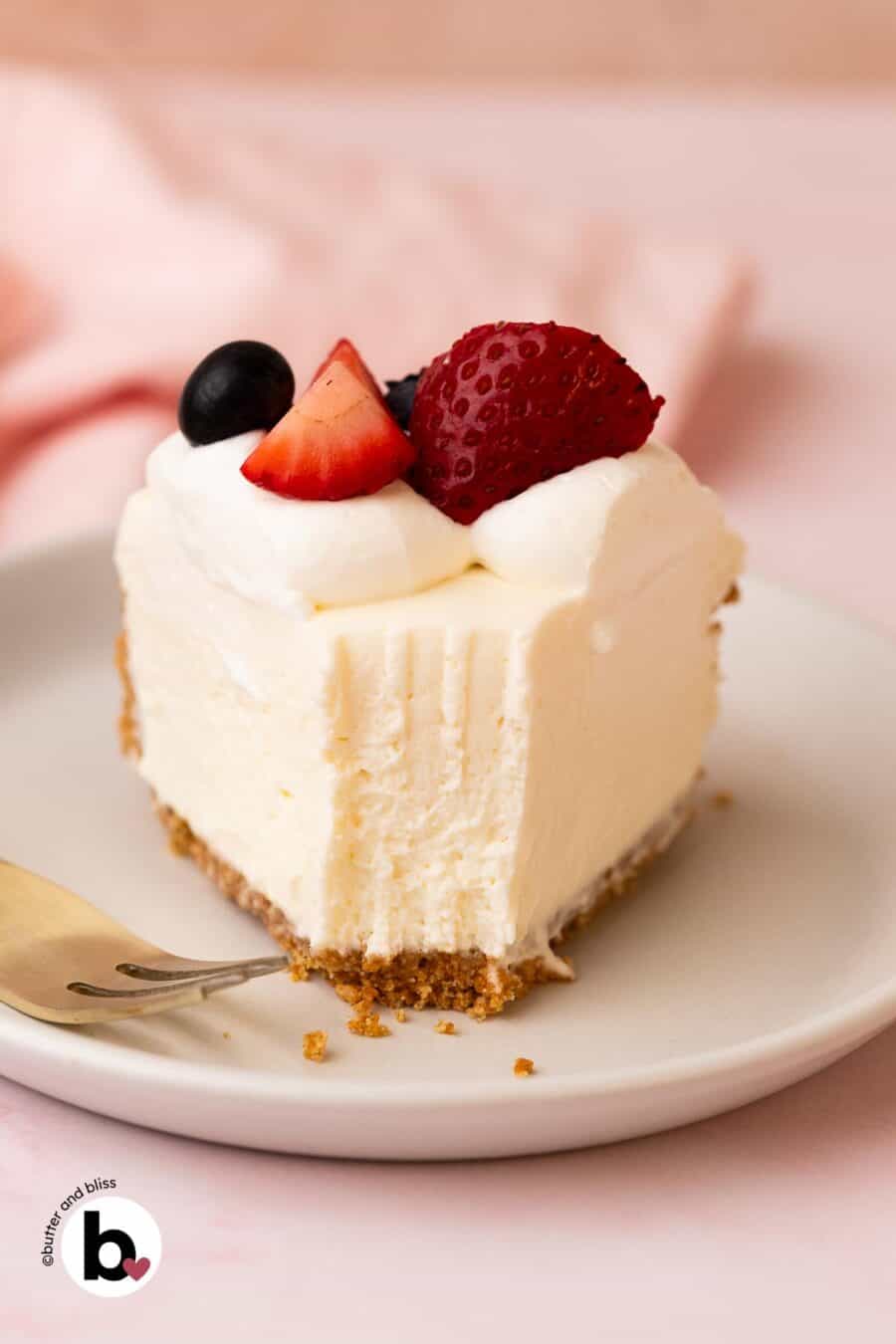 A slice of no-bake cheesecake on a white plate with a fork-bite taken out of it.