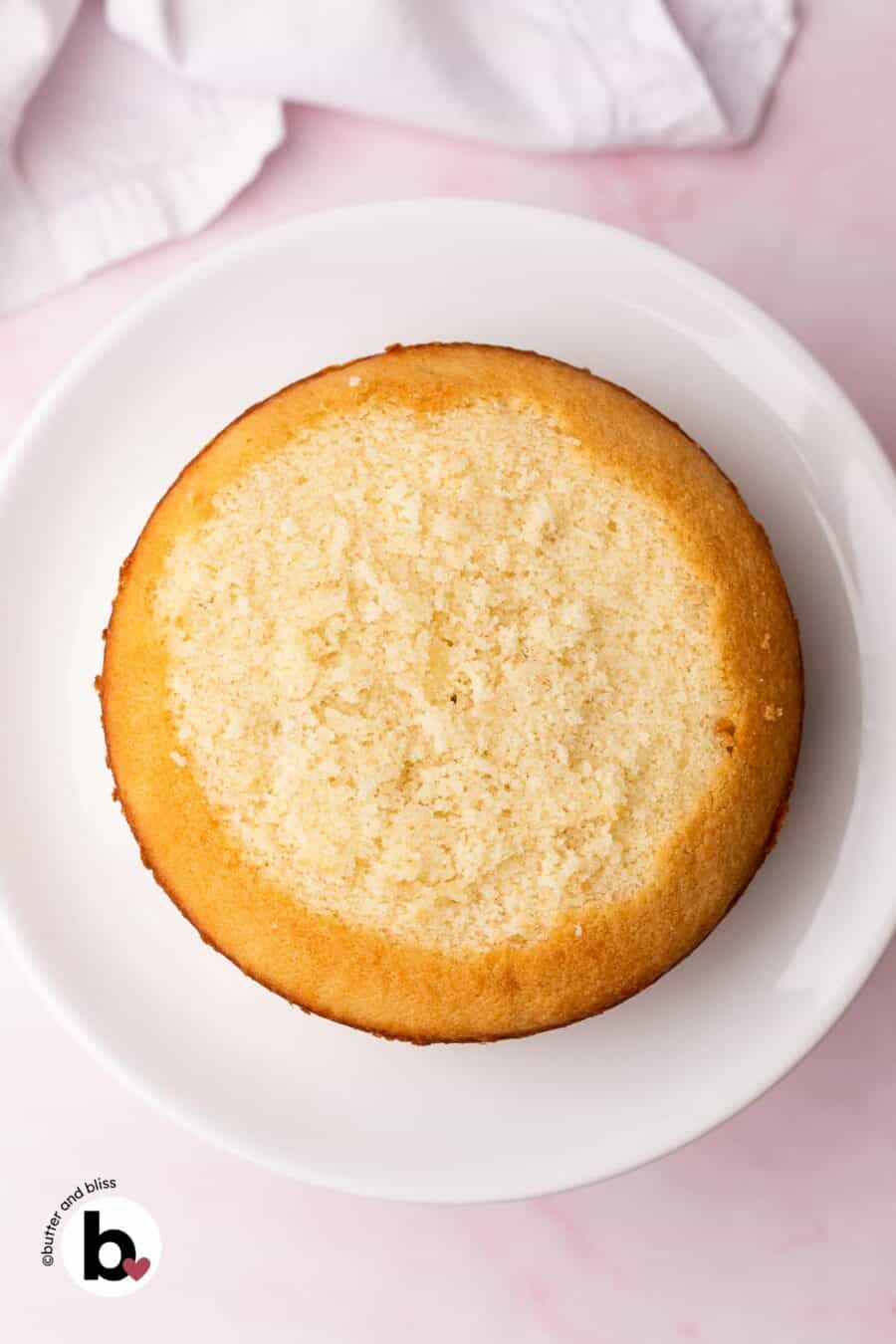 Small white cake with the domed top cut off on a white cake platter.
