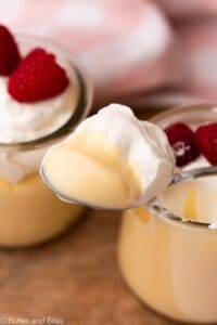 Creamy small batch vanilla pudding on a spoon with whipped cream.